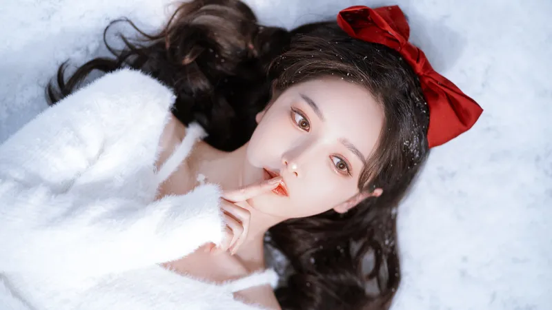 躺在雪地里的长发美女头戴红色蝴蝶结